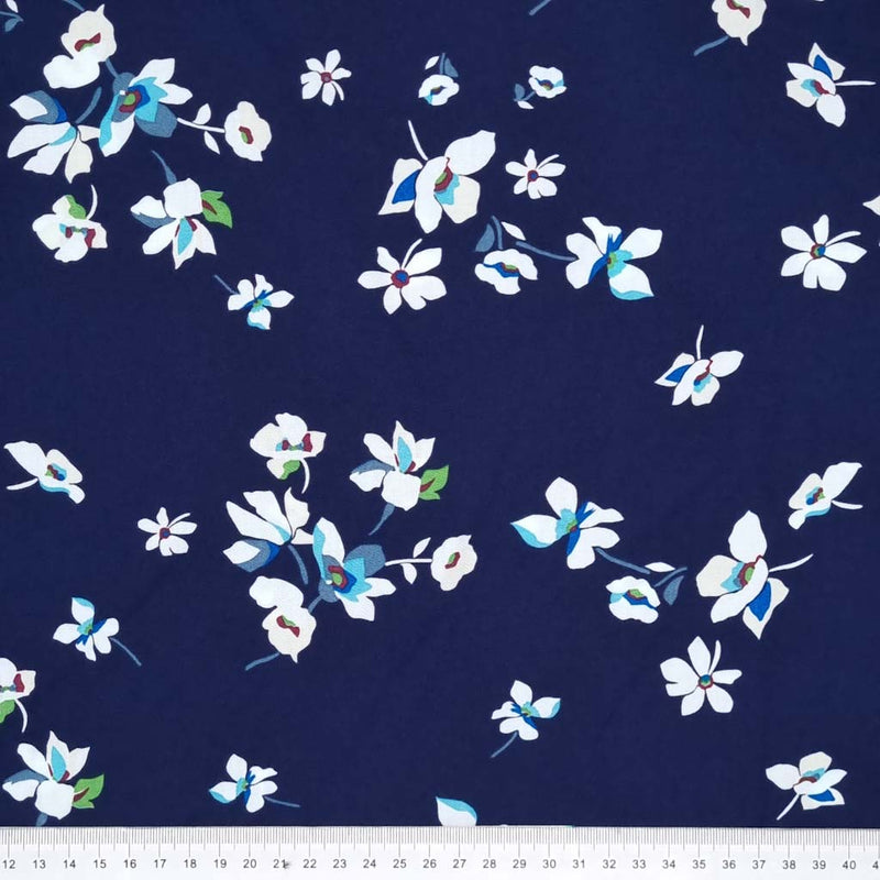 White flowers are printed on a navy blue viscose fabric with a cm ruler
