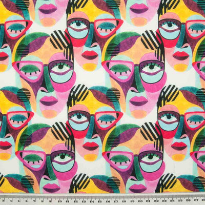 Abstract face paintings in vibrant pinks and greens are printed on a 100% cotton fabric by Little Johnny with a ruler for size perspective.
