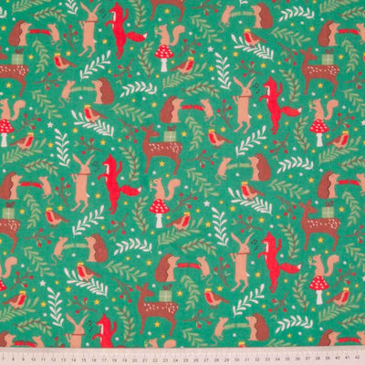 A collection of dancing forest animals enjoying a festive Christmas party, printed on a green polycotton fabric. Features rabbits, foxes, hedgehogs, robins and even a tiny mouse. With a ruler to give scale of image.
