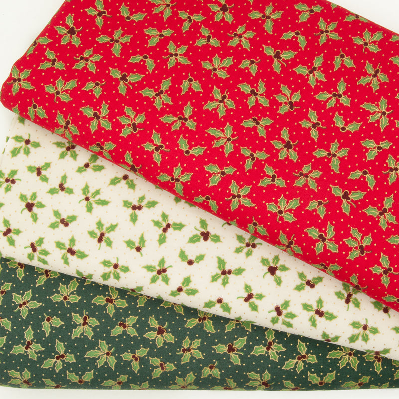 A fabric bundle of red, green and ivory christmas cottons printed with green and gold holly leaves in fan shape