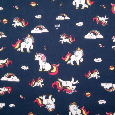 Cute white unicorns, colourful rainbows and stars are printed on a navy polycotton fabric