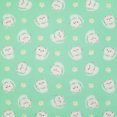 White cats with little daisies are printed on a mint polycotton fabric