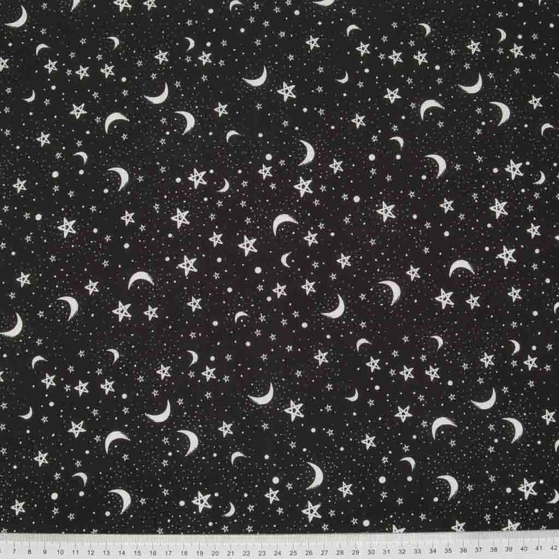 Small white stars and moons are printed in clusters on a black polycotton fabric with a cm ruler at the bottom