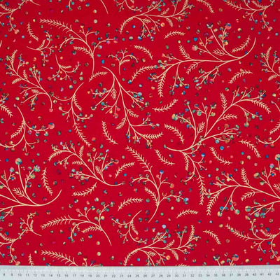 Rainbow coloured holly berries on festive branches printed on a red cotton fabric with a cm ruler at the bottom