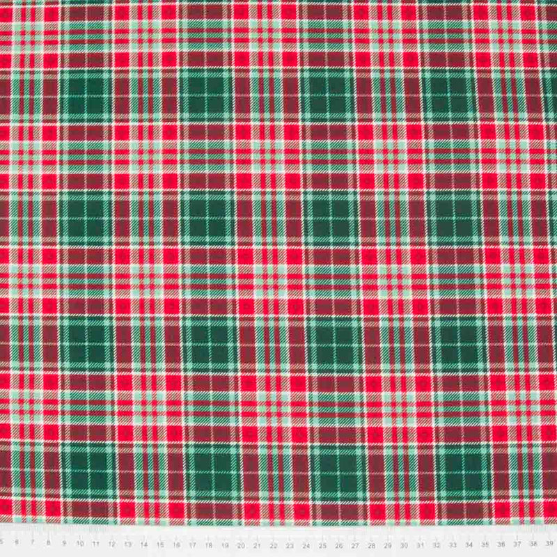 A 100% cotton christmas tartan plaid fabric with a dominant colour of forest green and red with a cm ruler at the bottom
