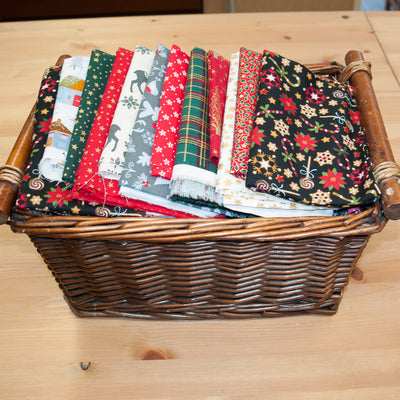 A wicker basket containing remnant pieces of christmas printed cotton fabric