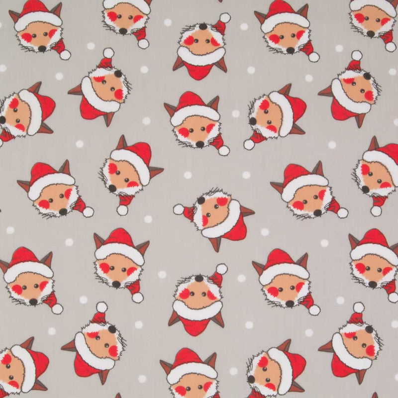 Cheeky fox faces wearing santa hats are printed on a silver polycotton christmas fabric