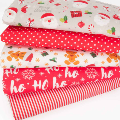 Five fat quarters of christmas polycotton fabric in reds and whites with Santa and gingerbread men