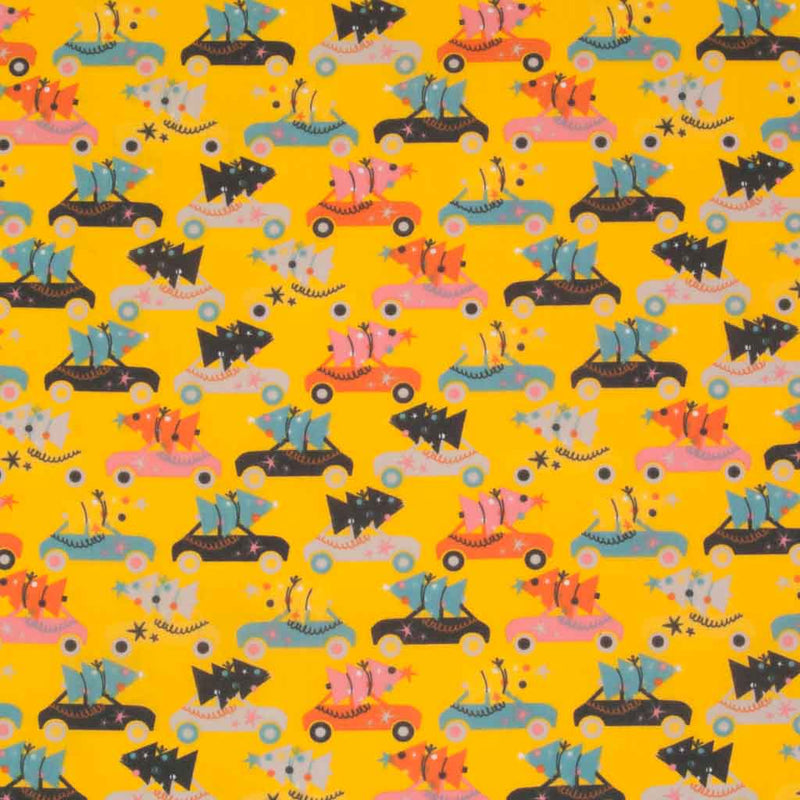 Rows of colourful cars carrying christmas trees are printed on a yellow polycotton fabric