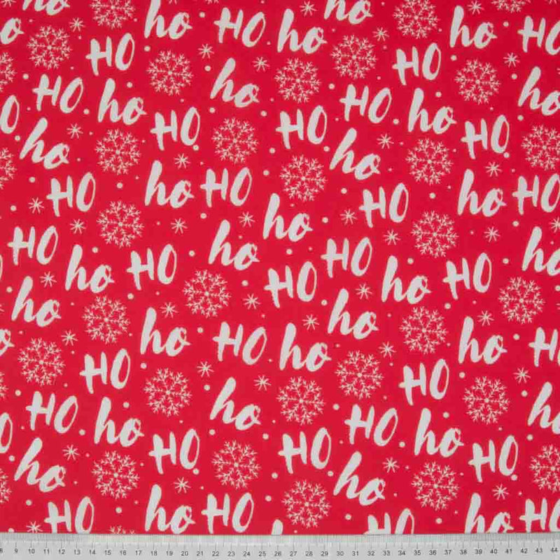 White festive Ho ho hos are printed on a red polycotton fabric. with a cm ruler at the bottom