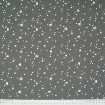 White christmas stars printed on a green polycotton fabric. with a cm ruler at the bottom