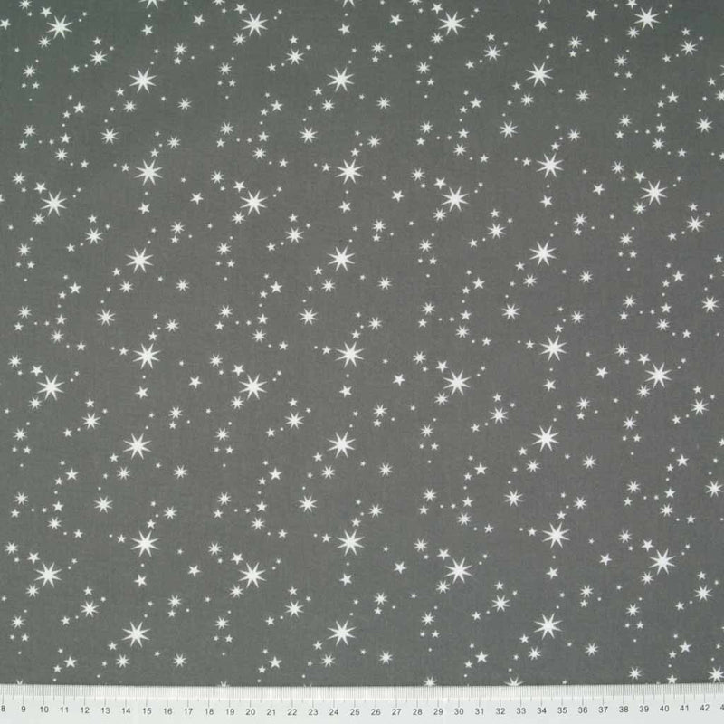 White christmas stars printed on a green polycotton fabric. with a cm ruler at the bottom