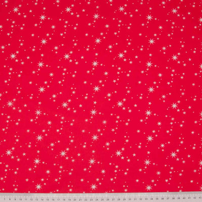 White christmas stars printed on a red polycotton fabric with a cm ruler at the bottom