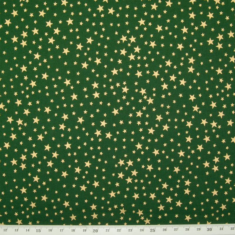A green christmas cotton fabric featuring small metallic gold stars in a tossed pattern including a ruler for perspective