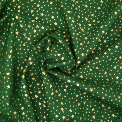 A green christmas cotton fabric featuring small metallic gold stars in a tossed pattern in a decorative swirl