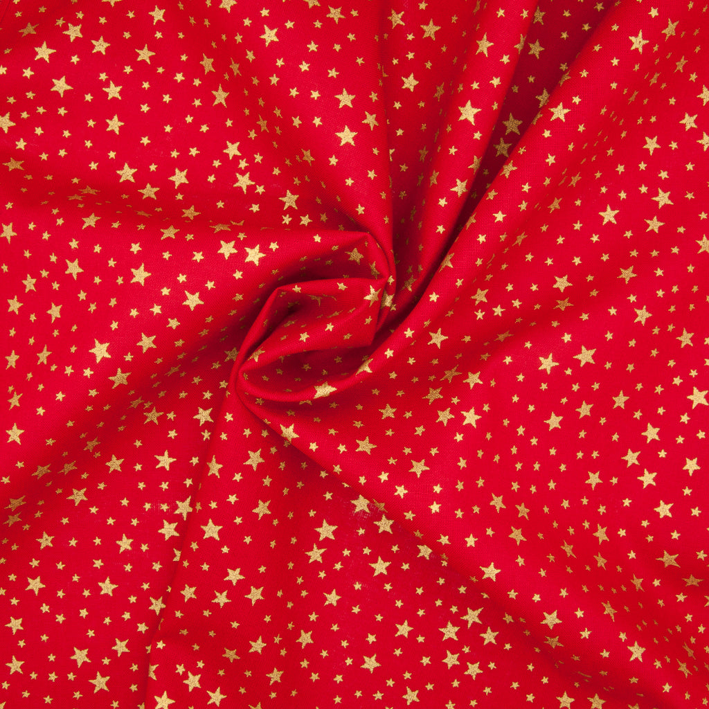 A red christmas cotton fabric featuring small metallic gold stars in a tossed pattern in a decorative swirl
