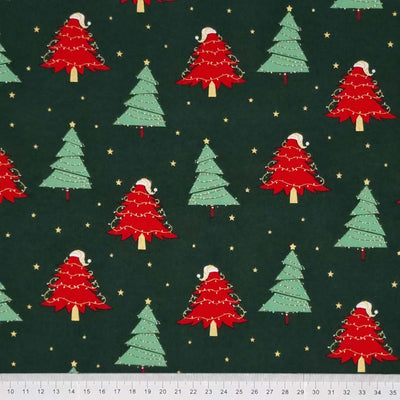 Red and green Christmas trees with metallic gold fairy lights and stars printed on a bottle green 100% quality cotton fabric by Rose & Hubble with ruler