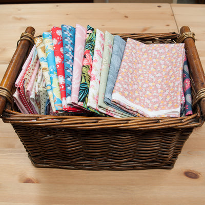 A wicker basket containing remnant pieces of floral printed cotton fabric