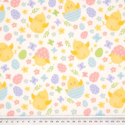 Easter chicks, flowers and eggs are printed on a white cotton fabric by Rose & Hubble with a cm ruler
