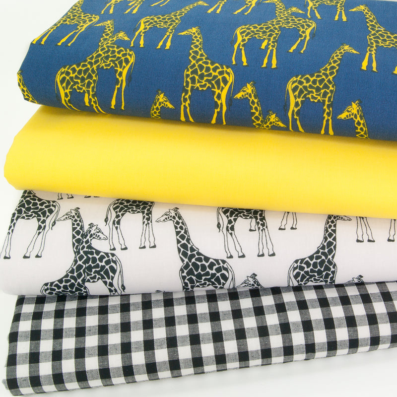 A fat quarter bundle of polycotton fabric prints showing yellow giraffes on a blue background and black and white giraffes