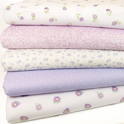 Five lilac polycotton floral fabric prints are arranged in a fat quarter bundle
