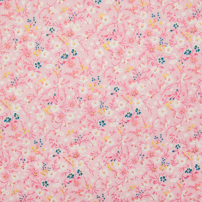 White, pink and blue ditsy flowers are printed on a pink polycotton fabric