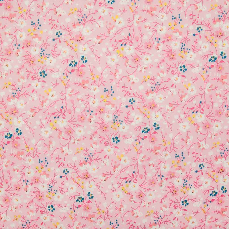 White, pink and blue ditsy flowers are printed on a pink polycotton fabric