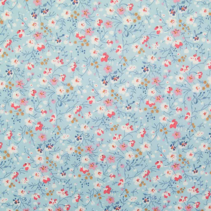 White, pink and blue ditsy flowers are printed on a sky blue polycotton fabric