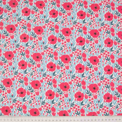 Small red poppy flowers with teal foliage are printed on a white polycotton fabric with a cm ruler at the bottom