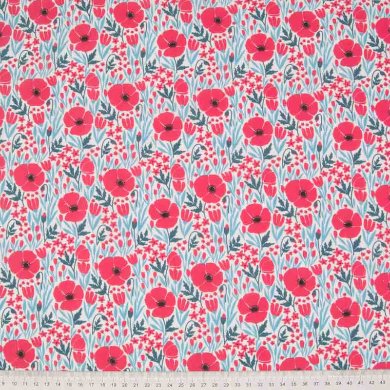 Small red poppy flowers with teal foliage are printed on a white polycotton fabric with a cm ruler at the bottom