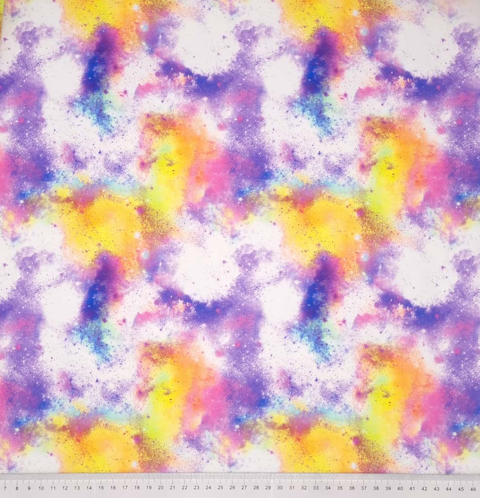 A spray painted style design made up of pinks, purples and yellows are printed on a white stretch french terry fabric by Little Johnny with a cm ruler at the bottom