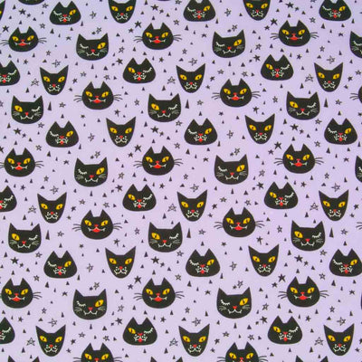 Halloween polycotton fabric printed with winking black cats on a lilac background