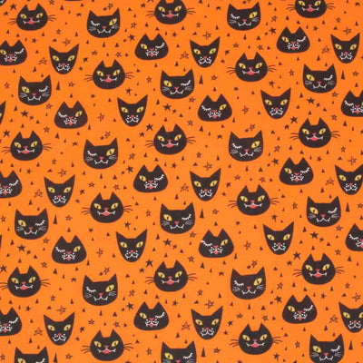 A halloween polycotton fabric printed with winking black cats on an orange background