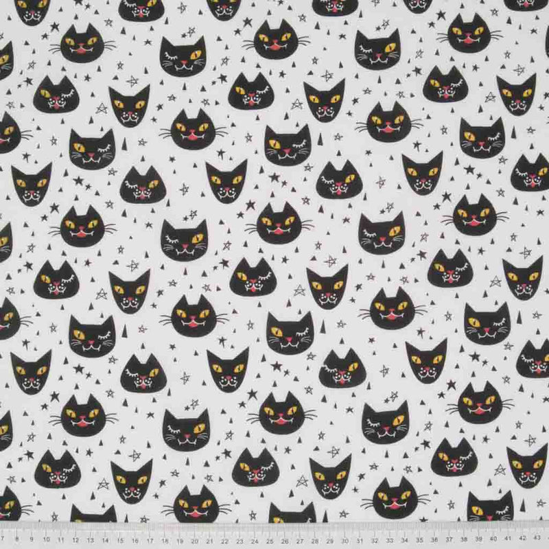 Winking black Halloween cats printed on a white polycotton fabric with a cm ruler at the bottom