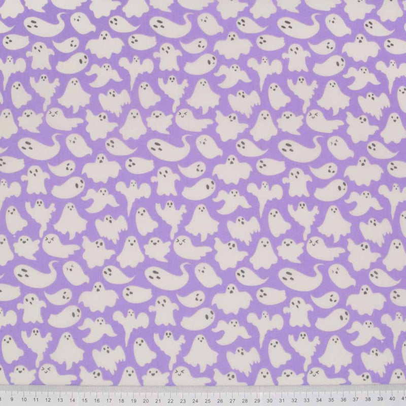 Small white halloween ghosts printed on a lilac polycotton fabric with a cm ruler at the bottom