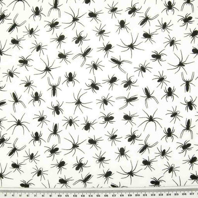 Black spiders printed on a white polycotton halloween fabric with a cm ruler at the bottom
