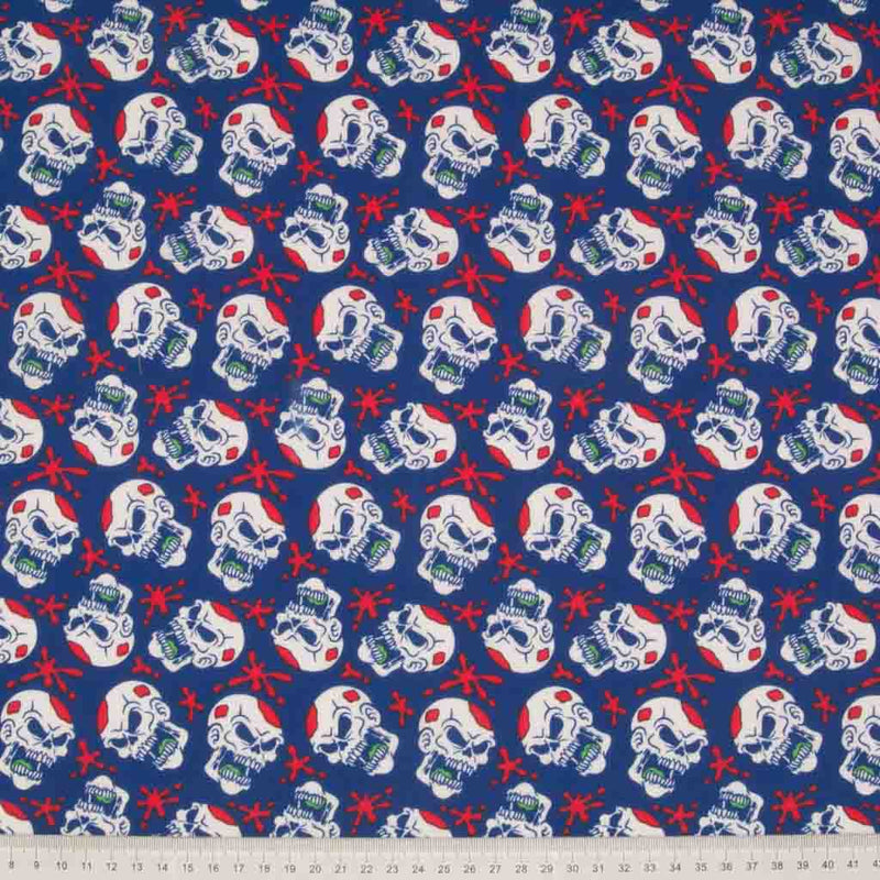 White screaming skulls and red paint splats printed on a blue halloween polycotton fabric with a cm ruler at the bottom