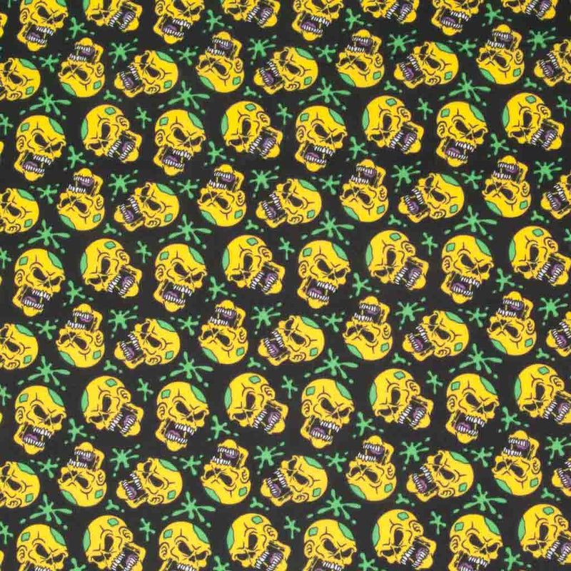 Yellow screaming skulls and green paint splats printed on a black halloween polycotton fabric