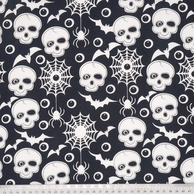 Skulls, eyeballs and bats printed on a black halloween polycotton fabric with a cm ruler at the bottom