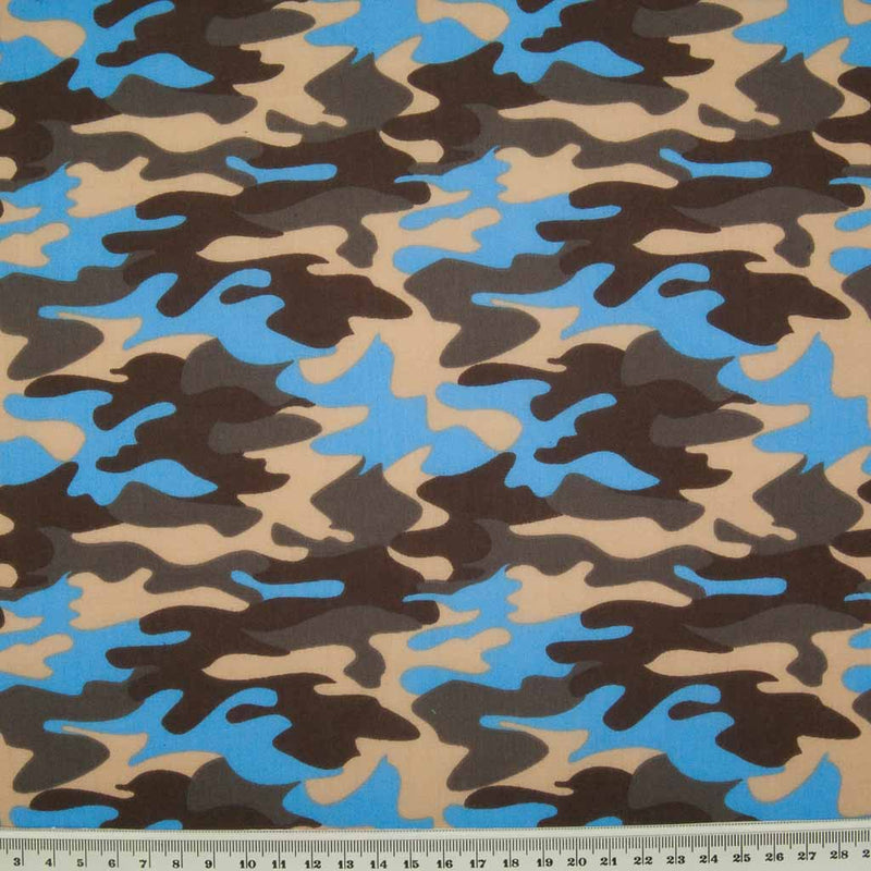 A camouflage design in beige, brown and blue on a polycotton fabric with a ruler at the bottom for size perspective