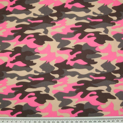 A camouflage design in beige, brown and hot pink on a polycotton fabric with a ruler at the bottom for size perspective