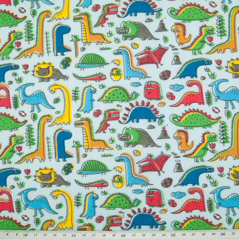 colourful cartoon dinosaurs printed on a blue polycotton fabric with a cm ruler