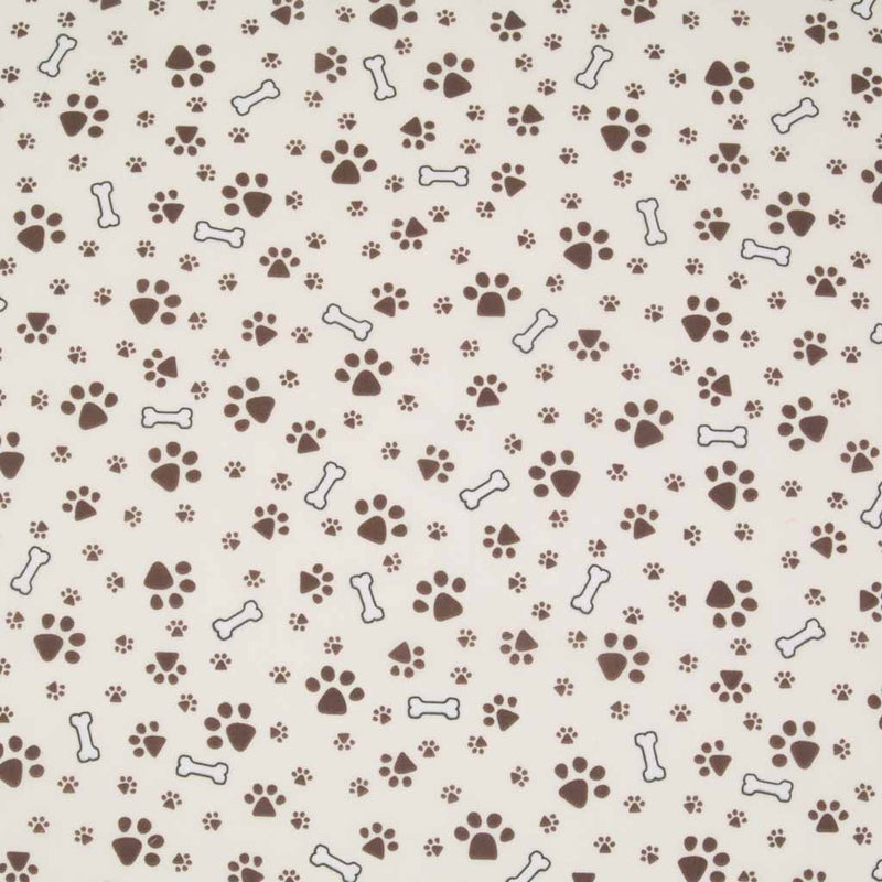Small muddy brown dog paw prints and white bones are printed on a cream polycotton fabric