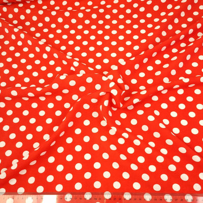 White polka dots on a red rayon fabric with a cm ruler at the bottom