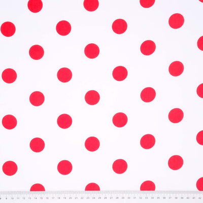 A 25mm cherry red spot printed on white polycotton fabric with a cm ruler at the bottom