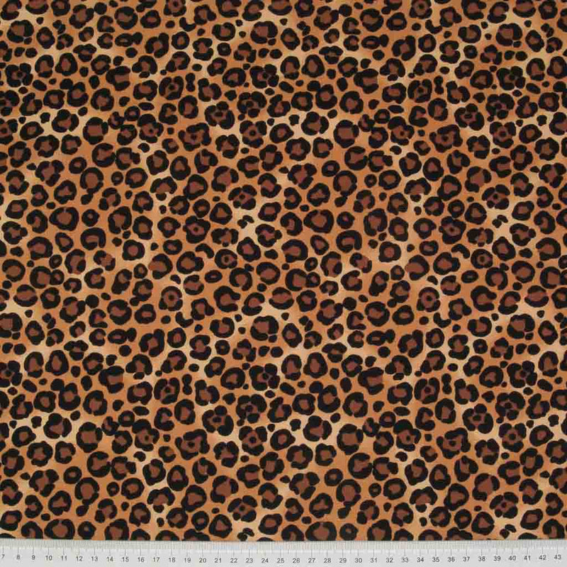 A natural coloured leopard print cotton fabric by Rose & Hubble with a cm ruler at the bottom