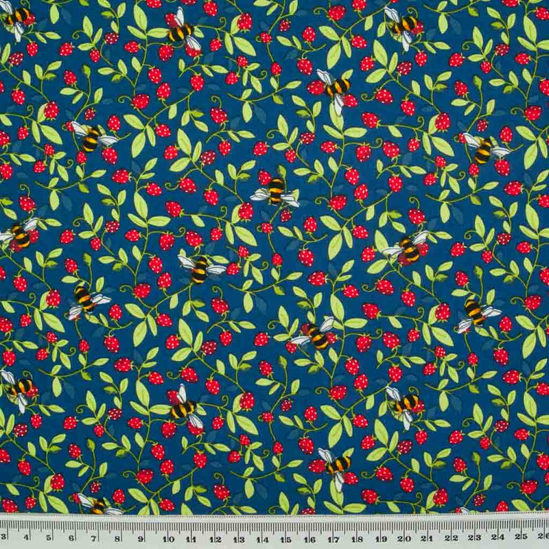 Small red strawberries and yellow bees are printed on a navy cotton poplin fabric by Rose & Hubble with a cm ruler at the bottom