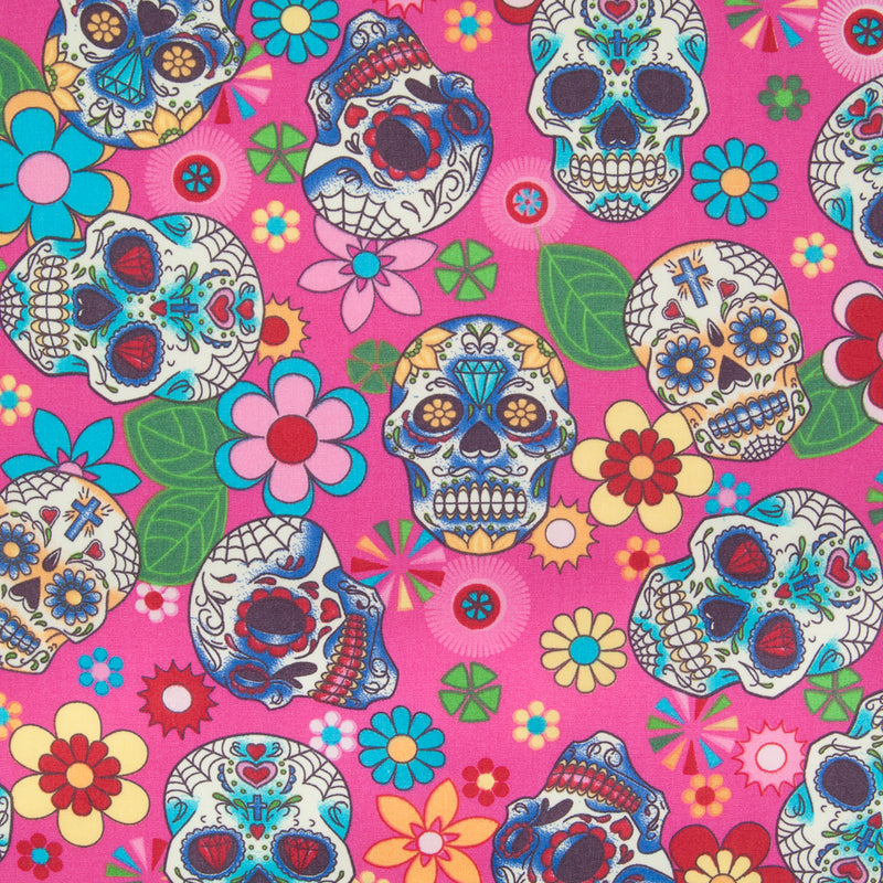A Rose & Hubble cotton fabric with bright and colourful skulls and flowers printed on a cerise background 