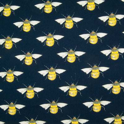 Large black and yellow bees in a geometric pattern on a flat piece of navy blue cotton poplin fabric