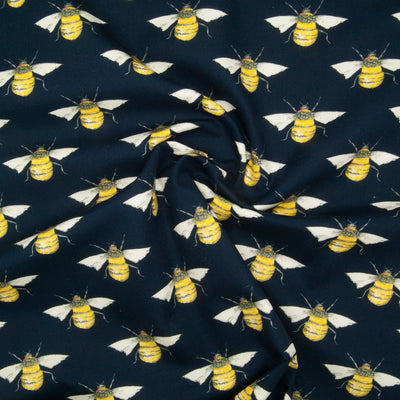 Large black and yellow bees in a geometric pattern on a flat piece of navy blue cotton poplin fabric in a swirl for drape perspective